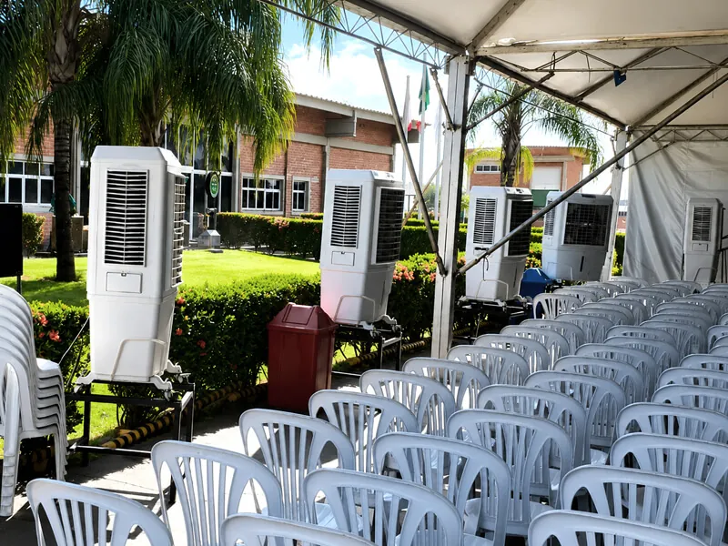 Climatizadores da K10 enfileirados na lateral de uma tenda com cadeiras montadas para o evento